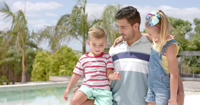 Happy caucasian father with children talking at swimming pool at beach house