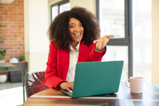 pretty afro black woman smiling happily and offering or showing a concept. businesswoman and laptop concept