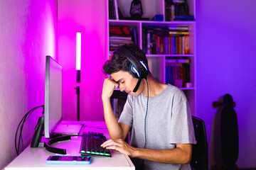 Fototapeta na wymiar Gamer feeling frustrated after losing an online gaming match on his computer