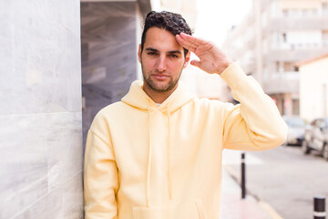 Fototapeta premium young hispanic man greeting the camera with a military salute in an act of honor and patriotism, showing respect