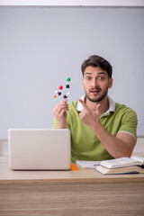 Young male student physicist sitting in the classroom