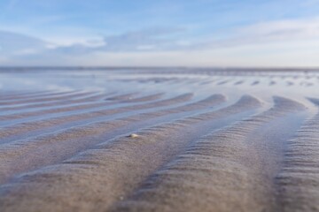 Wellenartige Muster im Flachwasser am Ostseeufer vor blauem Himmel. Ein atemberaubendes Naturphänomen eingefangen in einem Foto.