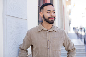 young handsome man smiling happily with a hands on hip and confident, proud and friendly attitude