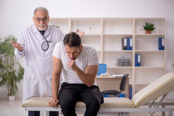 Fototapeta premium Young male patient visiting old male doctor