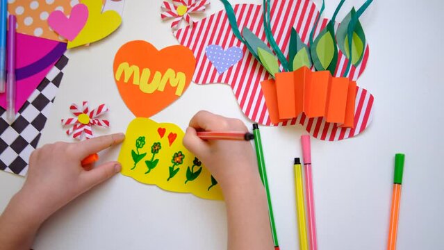 Child creating homemade greeting card. Paper vase with bouquets of flowers and hearts, gift for Mothers day, Birthday or Valentines day . Arts  crafts concept. Preshool crafts