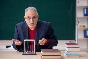 Old male teacher physicist sitting in the classroom