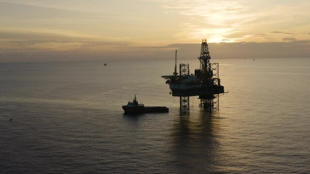 Jack up drilling rig and production platform in the middle of the ocean at sunrise time
