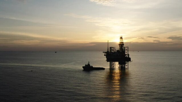 Jack up drilling rig and production platform in the middle of the ocean at sunrise time
