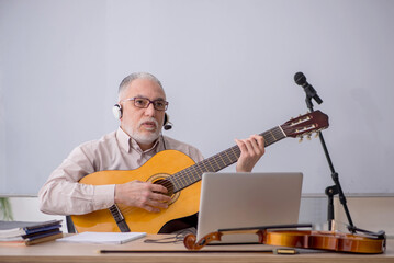 Old male music teacher in the classroom