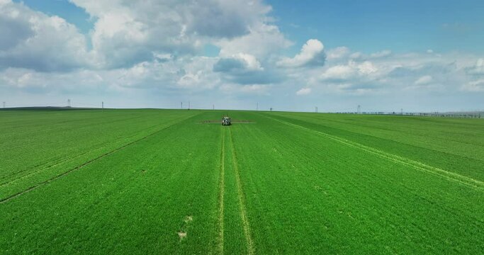 Tractor sprinkler fertilizer on green wheat field in farm during springtime 4k video