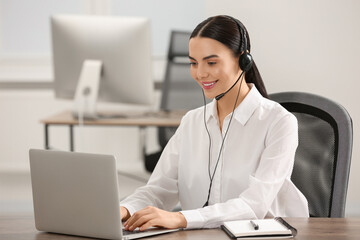 Hotline operator with headset working on laptop in office