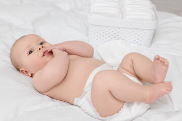 Cute baby and diapers on white bed