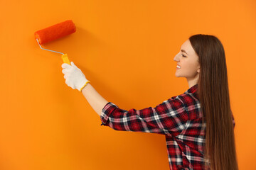 Happy designer painting orange wall with roller