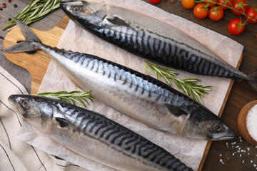 Raw mackerel, tomatoes and rosemary on wooden table, flat lay