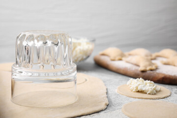 Process of making dumplings (varenyky) with cottage cheese. Raw dough and ingredients on grey table, closeup