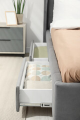 Storage drawers with bedding under modern bed in room, closeup