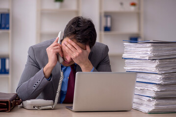 Young male employee and too much work in the office