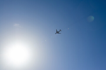 太陽に向かって青空を飛ぶ飛行機
