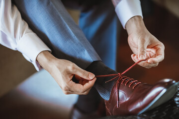 Handsome men tying their stylish shoe laces. The appearance of a business man. Details of the suit and the overall look.
