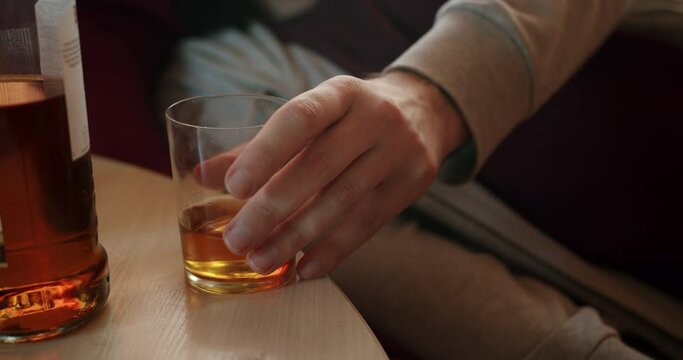 Alcoholic man with an alcohol addiction problem drinking daytime. Want to kill hangover. Binge drinking. Whiskey glass and whiskey bottle