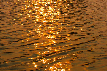 Gold water with ripples on the surface. Defocus blurred transparent gold colored clear calm water...