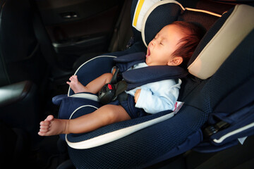 sleepy newborn baby yawning while sitting in infant car seat, safety chair travelling