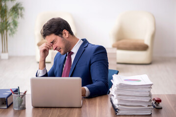 Young male employee unhappy with excessive work in the office