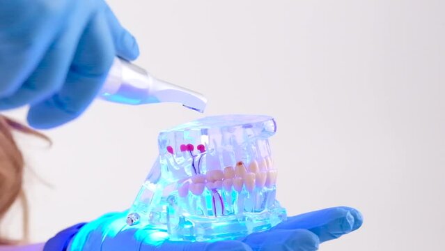 Photopolymer lamp Doctor Fairy with a glowing blue lamp in a white medical suit Dentist treatment of teeth prosthetics put fillings treat gums caries beautiful woman on white background studio ad