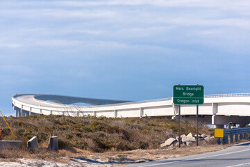 Road sign for Marc Basnight Bridge, Pea Island National Wildlife Refuge. Bridge curving away...