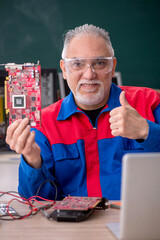 Old repairman repairing computers in the classroom