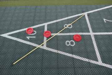 Shuffleboard court with cue and pucks on top