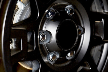 Fototapeta na wymiar Close up of a Black Car Rim and Tire with Chrome Lug Nuts