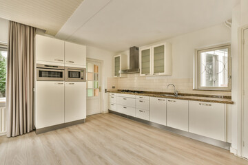 a white kitchen with wood flooring and an open door leading to the living room that has been used for several years