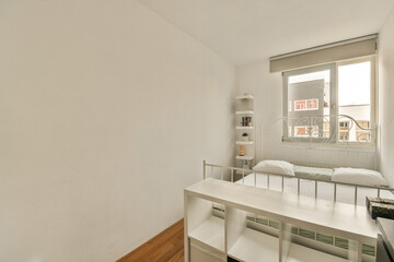 a bedroom with a bed, desk and mirror on the wall behind it is a window that looks out onto the street