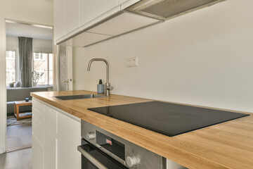 a kitchen with wood counter tops and white cabinets in the back, an open door leads to a living room