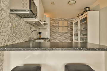 a kitchen with two stools in front of the counter top and wall tiles on the backs of the cabinets