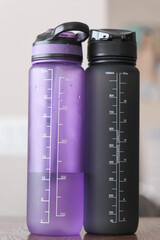 Black and purple water bottles on a table at home.
