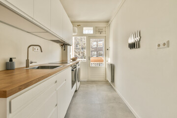 a long narrow kitchen with white cabinets and wood counter tops on the floor, along with an open door that leads to a balcony
