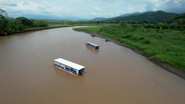 Muddy winding Tarcoles River in Costa Rica with Boats and green vegetation