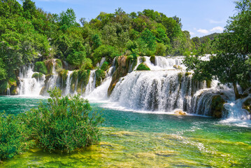 Fototapeta premium Beautiful Waterfall background in sunny summer day. Beautiful Waterfall In Krka National Park - Croatia, Europe. Krka river waterfalls in the Krka National Park