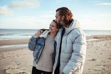 Young adult couple walking on a beach during cold weather
