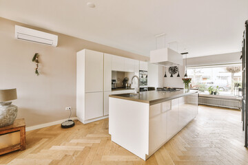 a kitchen and dining area in a house with wood floors, white cabinets and an open door leading to the patio