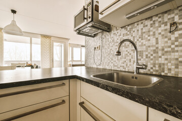 a kitchen with black and white tiles on the backs, counter tops, and sink fauced in it