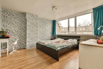 a bedroom with floral wallpaper on the walls and wood flooring in front of bed, desk and window