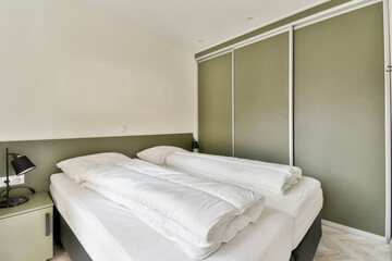 a bed in a room with green walls and white sheets on the bedspremnwhitt is visible