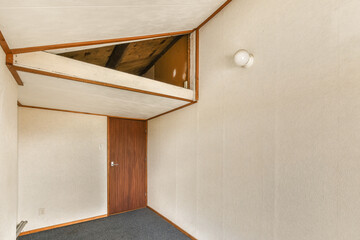 an empty room with wood trim on the ceiling and carpeting around the corner, looking up at the wall