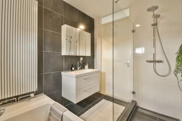 a modern bathroom with black and white tiles on the walls, sink, mirror, and shower stall in it