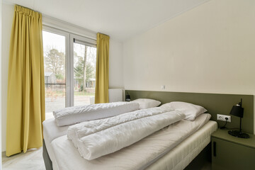 a hotel room with two beds and yellow drapes on the window is looking out onto an outside patio area