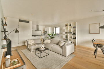 a living room with white walls and wood flooring in the center of the room there is a couch, chair, coffee table