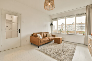 a living room with white tile flooring and an orange leather couch in front of the window looking out onto the street